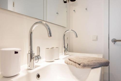 a white bathroom with two sinks and two faucets at lovely&cool STIL-HAUS in Fehmarn