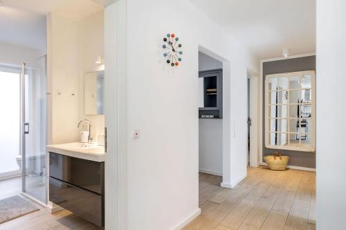 eine weiße Küche mit einem Waschbecken und einem Spiegel in der Unterkunft lovely&cool STIL-HAUS in Fehmarn