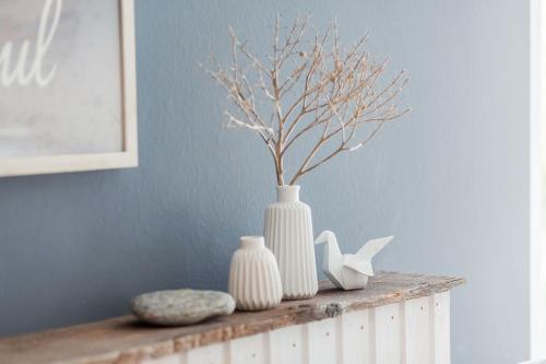 a shelf with two white vases and a plant on it at lovely&cool STIL-HAUS in Fehmarn