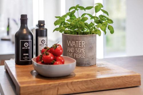 a plant and a bottle of wine and a bowl of tomatoes at lovely&cool STIL-HAUS in Fehmarn