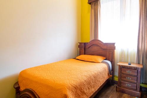 a bedroom with a bed and a dresser and a window at Casa Hotel Sura in San José