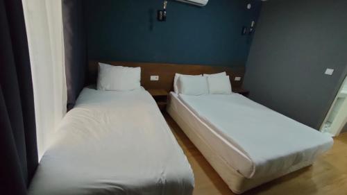 two beds in a room with white sheets at Beta GuestHouse in Antalya