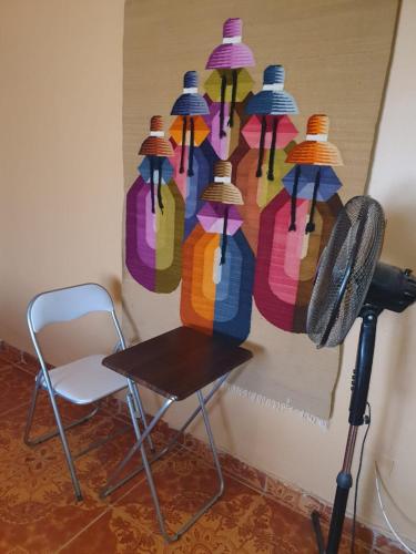 a chair and a painting of hats on a wall at Hostal Candelaria in San Pedro de Atacama