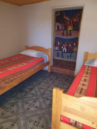 a room with two beds and a painting on the wall at Hostal Candelaria in San Pedro de Atacama