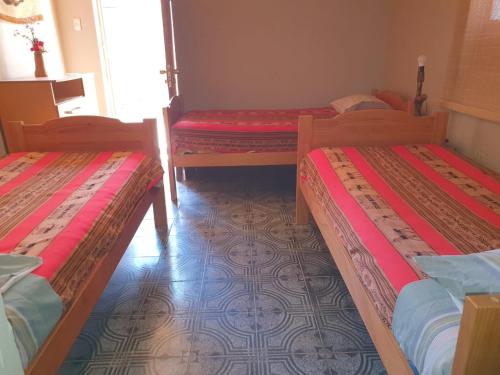 a room with three beds in a room at Hostal Candelaria in San Pedro de Atacama