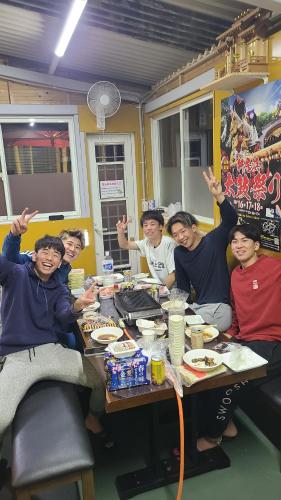 a group of people sitting at a table with their hands up at あかがね荘 in Sumino