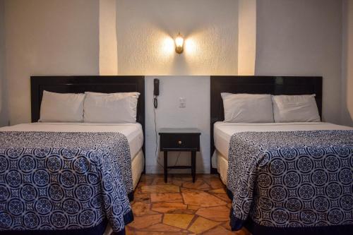 two beds in a room with two lamps on at Hotel Santa Ana in Mérida