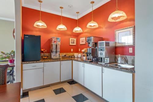 cocina con armarios blancos y paredes de color naranja en Big Lake Inn and Suites, en Big Lake