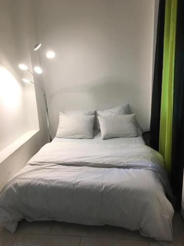 1 cama con sábanas blancas y almohadas en una habitación en Superbe & LUXURY studio Paris Montreuil, en Montreuil