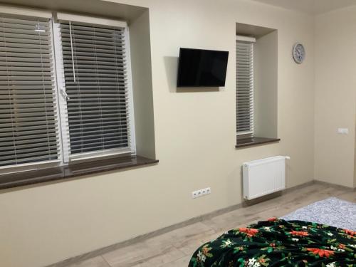 een slaapkamer met 2 ramen en een tv aan de muur bij LUX apartment & центр,ЖК Театральний in Rivne