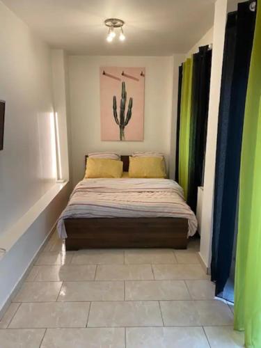 1 dormitorio con 1 cama con una pintura de cactus en la pared en Superbe & LUXURY studio Paris Montreuil, en Montreuil