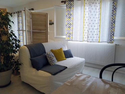 a living room with a white couch with blue and yellow pillows at Grand studio, super équipé, 2 pas du centre-ville "clos-du-boulanger" in Montbéliard