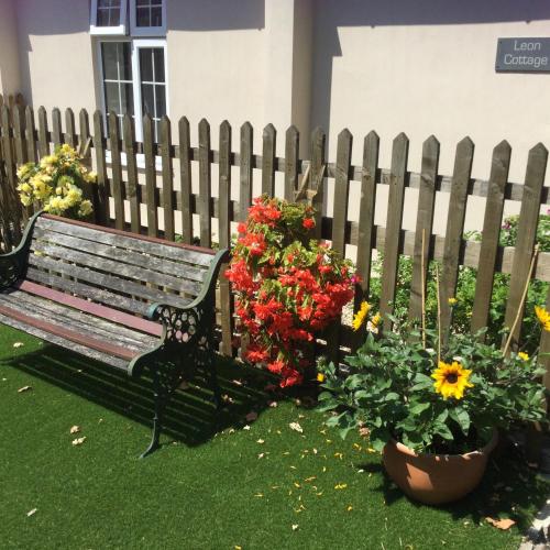 a park bench next to a fence with flowers at Leon Cottage in Thetford