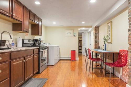 a kitchen with wooden cabinets and a table with red chairs at Parking - Private Entrance - King Beds in Boston