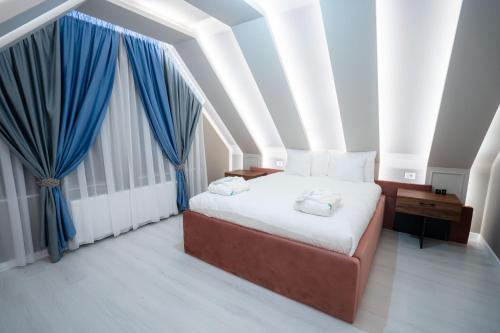 a bedroom with a large bed with blue curtains at SHIMresidence LUXURY in Rădăuţi