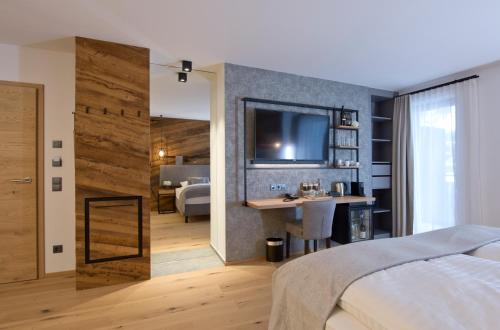a bedroom with a bed and a desk and a tv at Hotel Edelweiss in Saalbach Hinterglemm