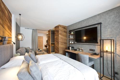 a bedroom with a bed and a desk and a tv at Hotel Edelweiss in Saalbach Hinterglemm