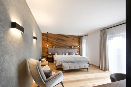 a bedroom with a bed and a chair at Hotel Edelweiss in Saalbach Hinterglemm