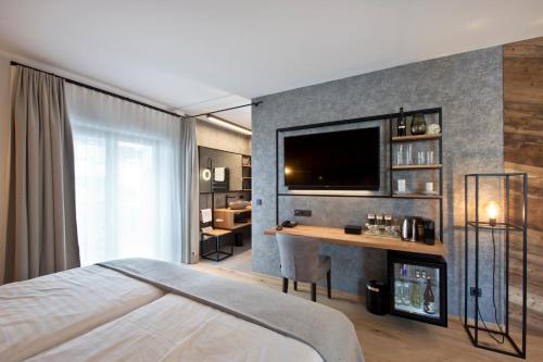a bedroom with a bed and a desk with a television at Hotel Edelweiss in Saalbach Hinterglemm