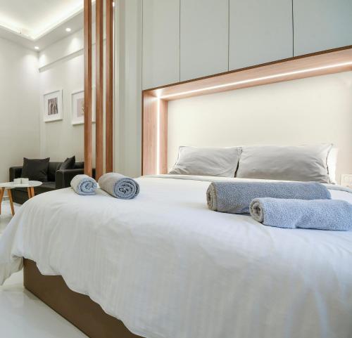 a bedroom with a large white bed with towels on it at #SKGH Anatolia & Amaryllis suites -NearHELEXPO in Thessaloniki