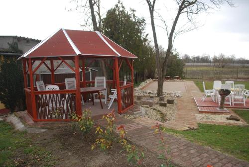 a gazebo with a table and chairs in a yard at Casa Napsugár Panzió in Apostag