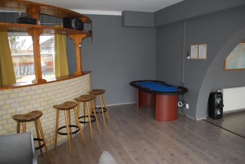 a bar with stools and a table in a room at Casa Napsugár Panzió in Apostag