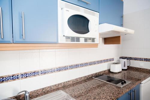 a kitchen with blue cabinets and a microwave at Mar Azul Playa in Puerto del Carmen