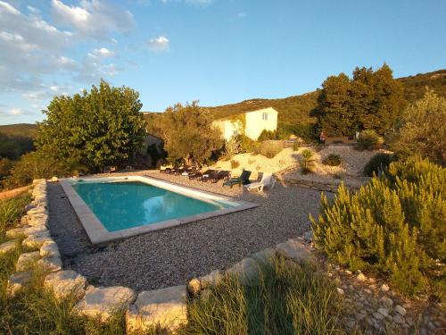 a swimming pool in a garden with a house in the background at Les agaves piscine panoramique vue exceptionnelle in Grospierres