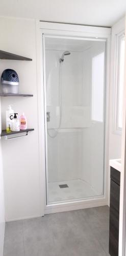 La salle de bains est pourvue d'une douche blanche avec une porte en verre. dans l'établissement Bungalow charmant à Onzain avec vue sur jardin, à Onzain