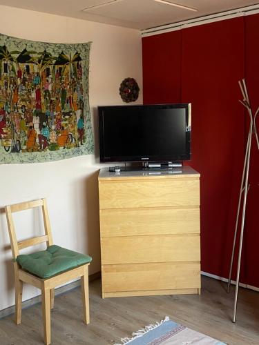 a living room with a television on a dresser with a chair at Gästehaus VillaVerde in Kelberg
