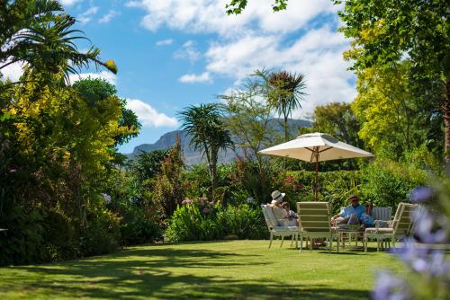 two people sitting in chairs under an umbrella in a garden at Last Word Constantia in Cape Town