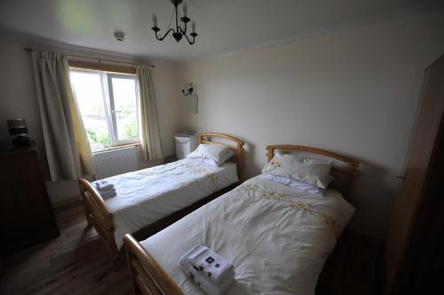 two twin beds in a room with a window at Sandwick Bay Guest House in Stornoway