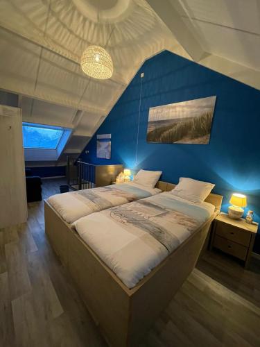a bedroom with a large bed with a blue wall at Lise's Place in Vrouwenpolder