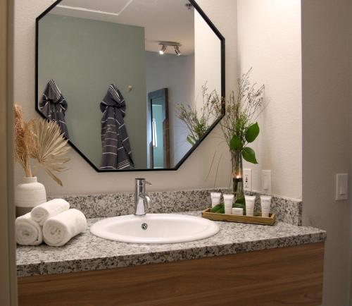 a bathroom sink with a large mirror and towels at Azure Palm Hot Springs in Desert Hot Springs