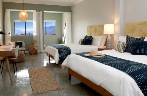 a hotel room with two beds and a desk at Azure Palm Hot Springs in Desert Hot Springs