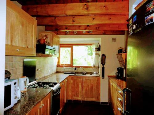 uma cozinha com armários de madeira e um forno com placa de fogão em Cabaña Adolim em San Martín de los Andes
