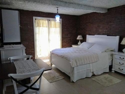 um quarto com uma cama branca e uma parede de tijolos em Apartamento no Centro de Gramado em Gramado