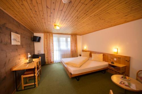 a hotel room with a bed and a desk and a table at Hotel Tenne in Reckingen - Gluringen