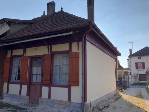 a small house with wooden windows and a roof at La maison des amis in Nuits