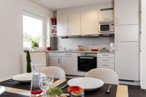 a kitchen with white cabinets and a table and chairs at Hotel & Apartments Böhm in Gravenwerth