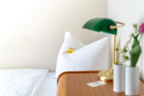a bed with a green lamp and a white pillow at Hotel & Apartments Böhm in Gravenwerth