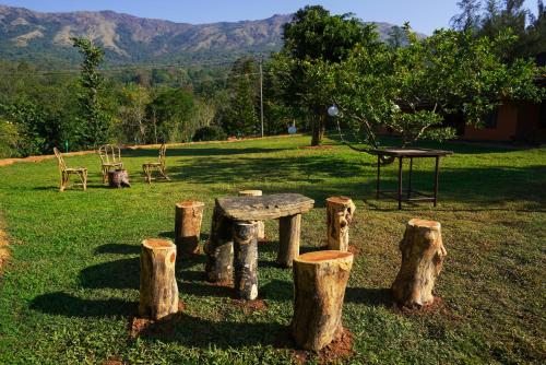 a picnic table and logs in a field with a table and chairs at Zostel Homes Wayanad, Thirunelly in Wayanad