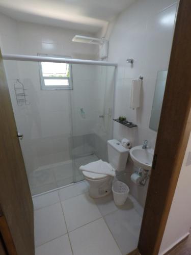 a bathroom with a shower and a toilet and a sink at Pousada Recanto das Margaridas in Boicucanga