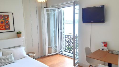 サン・セバスティアンにあるSEAFRONT LUXURY STUDIO - by www,SanSebastianApartments,esのベッドルーム1室(ベッド1台付)、バルコニー(テレビ付)