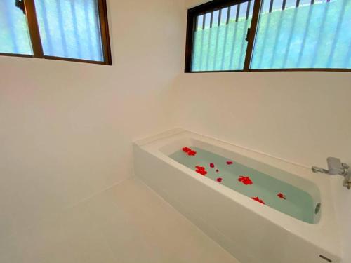 a white bath tub in a bathroom with two windows at Palm Villa Ishigakijima yugafu in Ishigaki Island
