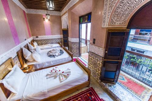 a bedroom with two beds and a balcony at Riad Atlas Mejbar in Marrakech
