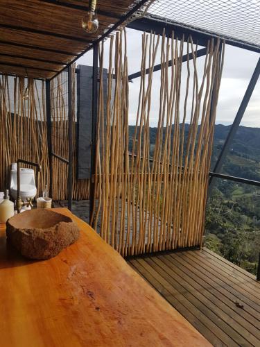 Habitación con mesa de madera y ventana grande. en Glamping La Montaña Sagrada en Medellín