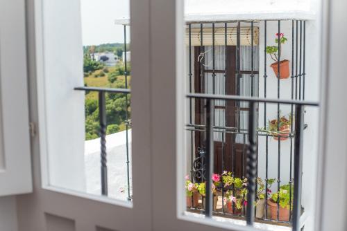 okno z widokiem na balkon z doniczkami w obiekcie Apartamento Trafalgar By La Juderia De Vejer - Inside a typical Andalusian Casa Patio w mieście Vejer de la Frontera