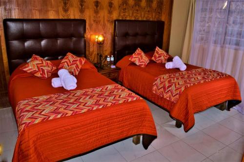 two beds in a hotel room with towels on them at Hotel "La Cabaña de Don Adolfo" in Zacatlán