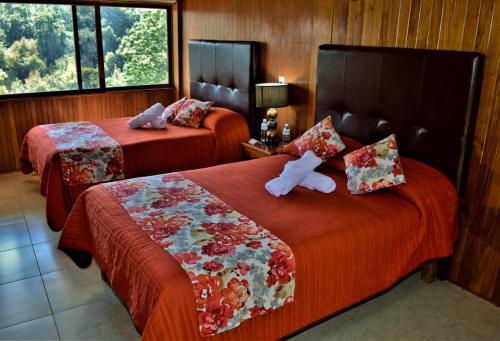 a hotel room with two beds with red sheets at Hotel "La Cabaña de Don Adolfo" in Zacatlán